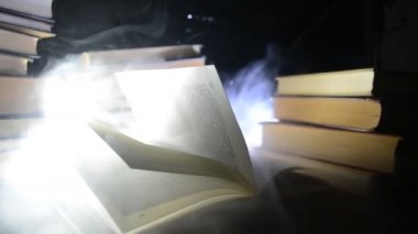 Bir yığın halinde birçok eski kitaplar. Knoledge kavramı. Duman elemanları ile karanlık bir arka plan üzerinde kitaplar. Merkezi büyülenmiş kitapta. Glasswatch