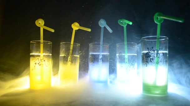 Five cocktails on the bar with smoke on dark background. Yellow, green and blue colored glasses. Club drinks — Stock Video