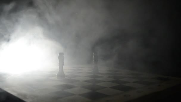 Jeu d'échiquier concept d'idées d'affaires et de la concurrence et des idées de stratégie concéder. Chess figures sur un fond sombre avec de la fumée et du brouillard. Concentration sélective — Video