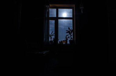 Gece manzarası karanlık odanın penceresinden görülüyor.