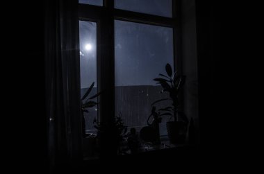 Gece manzarası karanlık odanın penceresinden görülüyor.
