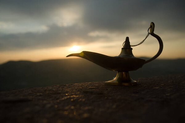 Антикварная ремесленная арабская ночь Аладдина в стиле джинна масляная лампа с мягким белым дымом. Закат горы
