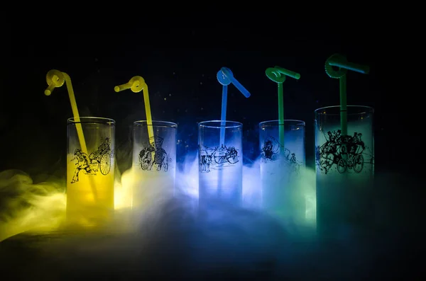 Cinco cócteles en el bar con humo sobre fondo oscuro. Gafas de color amarillo, verde y azul . — Foto de Stock