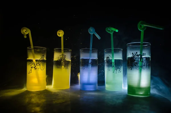 Cinco cócteles en el bar con humo sobre fondo oscuro. Gafas de color amarillo, verde y azul . —  Fotos de Stock