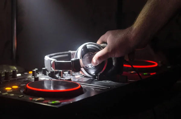 DJ Spinning, Mixing, and Scratching in a Night Club, Hands of dj tweak various track controls on dj's deck, strobe lights and fog, selective focus, close up. Dj Music club life — Stock Photo, Image