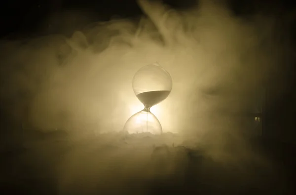Έννοια του χρόνου. Σιλουέτα κλεψύδρα ρολόι και καπνού σε σκούρο φόντο με ζεστό κίτρινο πορτοκαλί φωτισμός ή σύμβολα του χρόνου με αντίγραφο χώρου, κλεψύδρα ή Άμμος ρολόι — Φωτογραφία Αρχείου