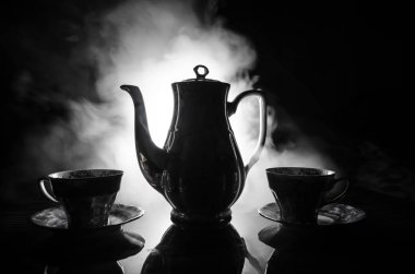 Gıda arka plan Tema çay ve kahve. Eski vintage seramik çay veya kahve ile ışık ve duman koyu arka plan üzerinde bardak sürahi ve şeker Kupası ile. Seramik çaydanlık ve bardak siluetleri.