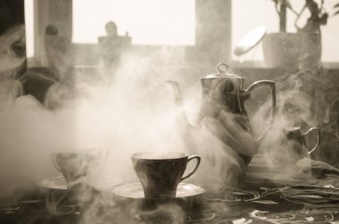 Gıda arka plan Tema çay ve kahve. Eski vintage seramik çay veya kahve ile ışık ve duman koyu arka plan üzerinde bardak sürahi ve şeker Kupası ile. Seramik çaydanlık ve bardak siluetleri.