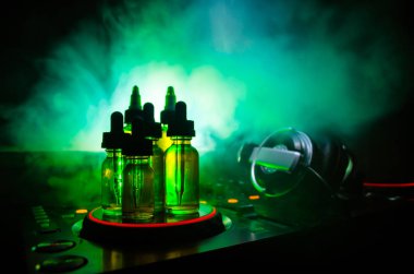 Vape ve Dj Club kavramı. Duman bulutları ve Dj Mikser yakın çekim vape sıvı şişe. Işık efektleri. Arka plan veya vape veya kulüp reklam ya da vape arka plan olarak yararlı.