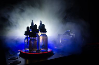 Vape ve Dj Club kavramı. Duman bulutları ve Dj Mikser yakın çekim vape sıvı şişe. Işık efektleri. Arka plan veya vape veya kulüp reklam ya da vape arka plan olarak yararlı.