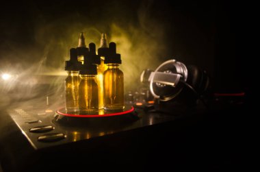 Vape ve Dj Club kavramı. Duman bulutları ve Dj Mikser yakın çekim vape sıvı şişe. Işık efektleri. Arka plan veya vape veya kulüp reklam ya da vape arka plan olarak yararlı.
