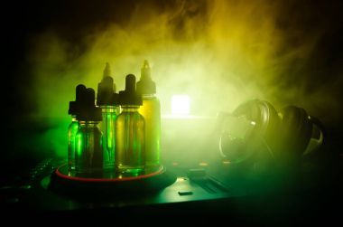 Vape ve Dj Club kavramı. Duman bulutları ve Dj Mikser yakın çekim vape sıvı şişe. Işık efektleri. Arka plan veya vape veya kulüp reklam ya da vape arka plan olarak yararlı.
