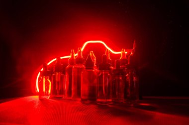 Vape kavramı. Duman bulutları ve vape sıvı şişe koyu arka plan üzerinde. Işık efektleri.