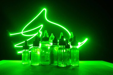 Vape kavramı. Duman bulutları ve vape sıvı şişe koyu arka plan üzerinde. Işık efektleri.