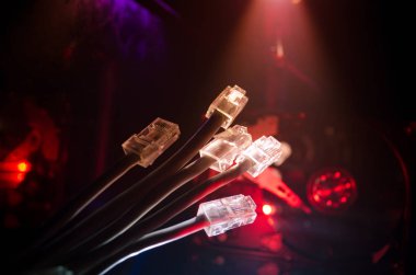 Ağ anahtarı ve ethernet kabloları, global iletişim sembolüdür. Işıklar ve duman ile koyu arka plan üzerinde renkli ağ kabloları. Seçici odak