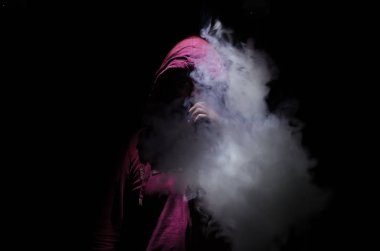 Bir mod tutarak Vaping adam. Buhar bulutu. Siyah arka plan. Vaping çok duman ile elektronik sigara.