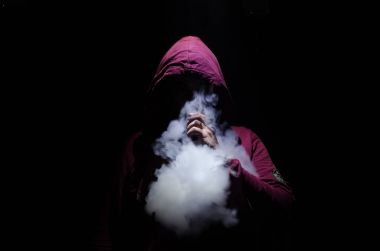 Bir mod tutarak Vaping adam. Buhar bulutu. Siyah arka plan. Vaping çok duman ile elektronik sigara.