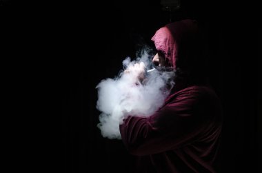 Bir mod tutarak Vaping adam. Buhar bulutu. Siyah arka plan. Vaping çok duman ile elektronik sigara.