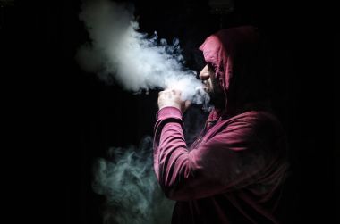 Bir mod tutarak Vaping adam. Buhar bulutu. Siyah arka plan. Vaping çok duman ile elektronik sigara.