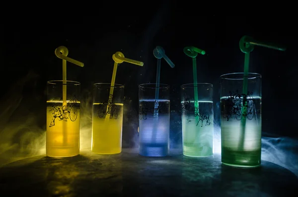 Five cocktails on the bar with smoke on dark background. Yellow, green and blue colored glasses. — Stock Photo, Image