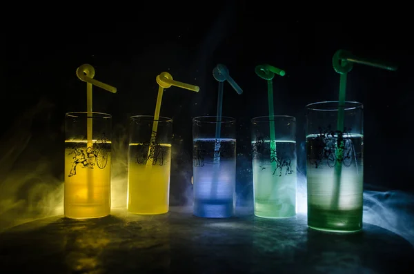 Cinco cócteles en el bar con humo sobre fondo oscuro. Gafas de color amarillo, verde y azul . —  Fotos de Stock