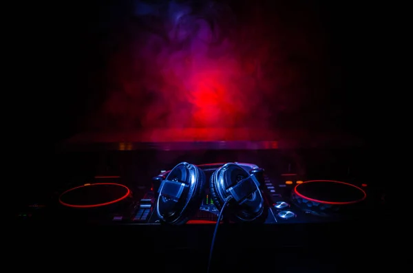 DJ Spinning, Mixing, and Scratching in a Night Club, Hands of Dj tweak various track controls on dj 's deck, strobe lights and fog, selective focus, close up. Концепция жизни клуба Dj Music — стоковое фото