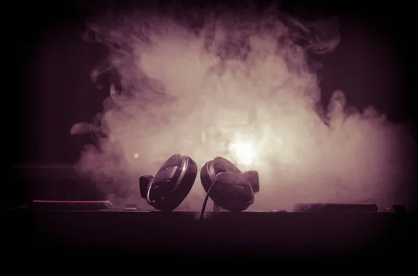 DJ Spinning, Mixing, and Scratching in a Night Club, Hands of Dj tweak various track controls on dj 's deck, strobe lights and fog, selective focus, close up. Концепция жизни клуба Dj Music — стоковое фото