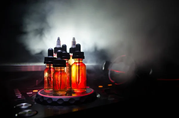 Concept de Vape et DJ Club. Fumez les nuages et vaporisez les bouteilles de liquide sur le mélangeur Dj. Effets de lumière. Utile comme fond ou vape ou publicité de club ou fond de vape . — Photo