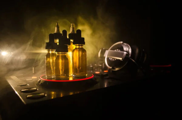 VAPE és klub Dj fogalom. Füst felhők és a vape folyékony üveg a Dj keverő közelről. Fényhatások. Hasznos háttér vagy vape vagy club hirdetés vagy vape háttérként. — Stock Fotó