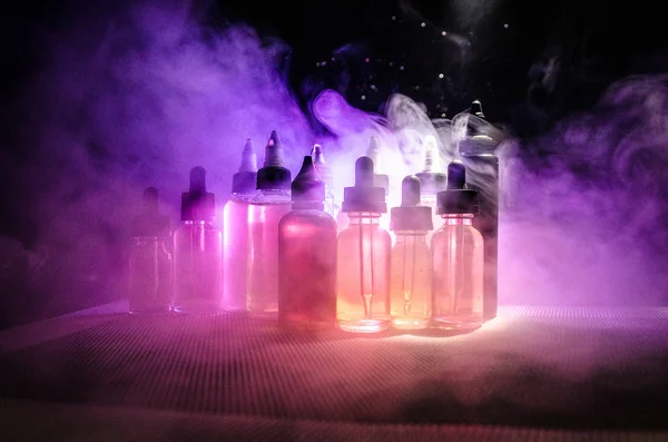 Vape concept. Smoke clouds and vape liquid bottles on dark background. Light effects. — Stock Photo, Image