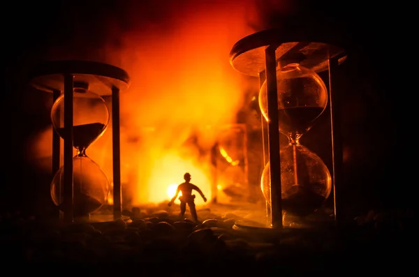 時間の概念。煙で砂時計、暗い背景上のライトの間に立って人のシルエット. — ストック写真