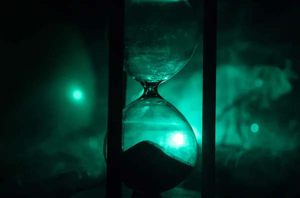 Time concept. Silhouette of a man standing between hourglasses with smoke and lights on a dark background. — Stock Photo, Image