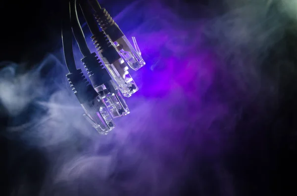 Conmutador de red y cables Ethernet, símbolo de las comunicaciones globales. Cables de red de color sobre fondo oscuro con luces y humo. Enfoque selectivo —  Fotos de Stock