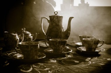 Gıda arka plan Tema çay ve kahve. Eski vintage seramik çay veya kahve ile ışık ve duman koyu arka plan üzerinde bardak sürahi ve şeker Kupası ile. Seramik çaydanlık ve bardak siluetleri