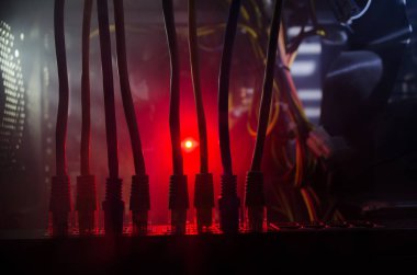 Ağ anahtarı ve ethernet kabloları, global iletişim sembolüdür. Işıklar ve duman ile koyu arka plan üzerinde renkli ağ kabloları. Seçici odak