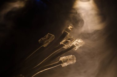 Ağ anahtarı ve ethernet kabloları, global iletişim sembolüdür. Işıklar ve duman ile koyu arka plan üzerinde renkli ağ kabloları. Seçici odak