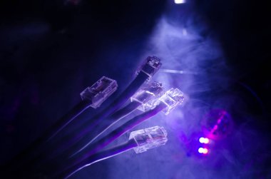 Ağ anahtarı ve ethernet kabloları, global iletişim sembolüdür. Işıklar ve duman ile koyu arka plan üzerinde renkli ağ kabloları. Seçici odak