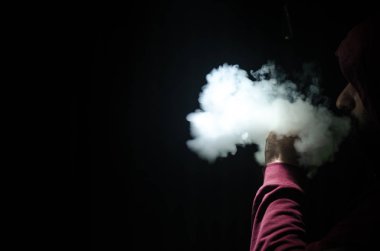 Bir mod tutarak Vaping adam. Buhar bulutu. Siyah arka plan. Vaping çok duman ile elektronik sigara
