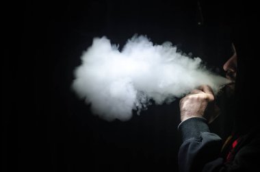 Bir mod tutarak Vaping adam. Buhar bulutu. Siyah arka plan. Vaping çok duman ile elektronik sigara
