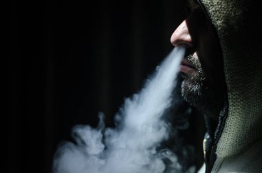 Bir mod tutarak Vaping adam. Buhar bulutu. Siyah arka plan. Vaping çok duman ile elektronik sigara