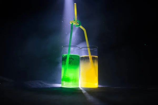 Яскраво-жовтий зелений коктейль, прикрашений лаймом. Класичні алкогольні коктейлі, алкогольні напої, безалкогольні напої, смачні коктейлі на темному фоні з димом і світлом — стокове фото