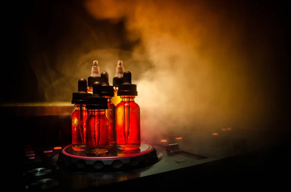 Concept de Vape et DJ Club. Fumez les nuages et vaporisez les bouteilles de liquide sur le mélangeur Dj. Effets de lumière. Utile comme fond ou vape ou publicité de club ou fond de vape . — Photo