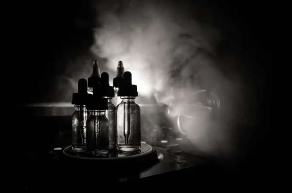 Il concetto di vaporizzatore e DJ Club. Nuvole di fumo e bottiglie di liquido vaporizzante sul mixer Dj da vicino. Effetti luce. Utile come sfondo o vaporizzare o pubblicità club o vaporizzare sfondo . — Foto Stock