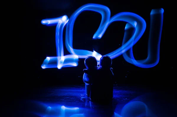 Два молодых любовника рисуют горящее сердце. Силуэт пары и слова любви на тёмном фоне — стоковое фото