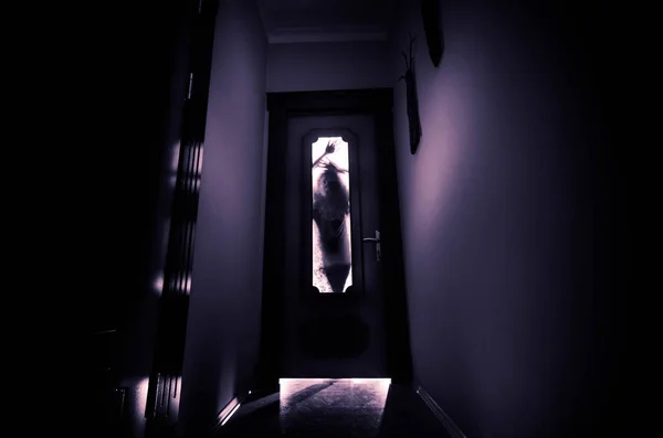 Силуэт неизвестной тени с руками на двери через закрытую стеклянную дверь. Концепция ужасов — стоковое фото