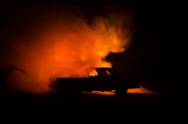 Carro a arder num fundo escuro. Carro pegando fogo, após ato de vandalismo ou estrada indicativo — Fotografia de Stock