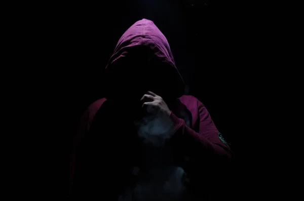 Homem a bater com um mod. Uma nuvem de vapor. Fundo preto. Vaping um cigarro eletrônico com muita fumaça — Fotografia de Stock