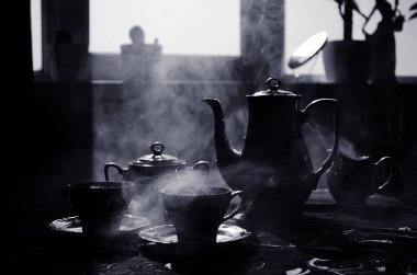 Gıda arka plan Tema çay ve kahve. Eski vintage seramik çay veya kahve ile ışık ve duman koyu arka plan üzerinde bardak sürahi ve şeker Kupası ile. Seramik çaydanlık ve bardak siluetleri