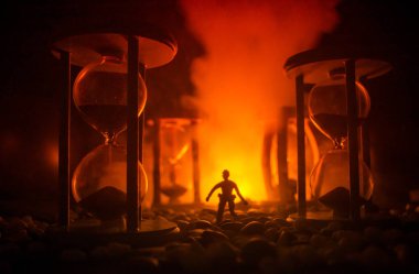 Zaman kavramı. Duman ile hourglasses ve karanlık bir arka plan ışıkları arasında duran bir adam silüeti.