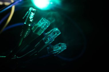 Ağ anahtarı ve ethernet kabloları, global iletişim sembolüdür. Işıklar ve duman ile koyu arka plan üzerinde renkli ağ kabloları. Seçici odak